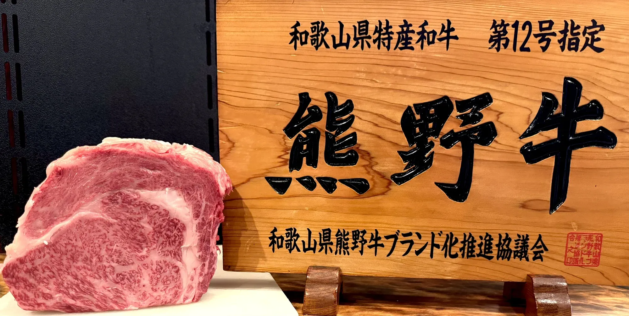 熊野牛指定店の看板「熊野牛」と、霜降りの熊野牛の塊