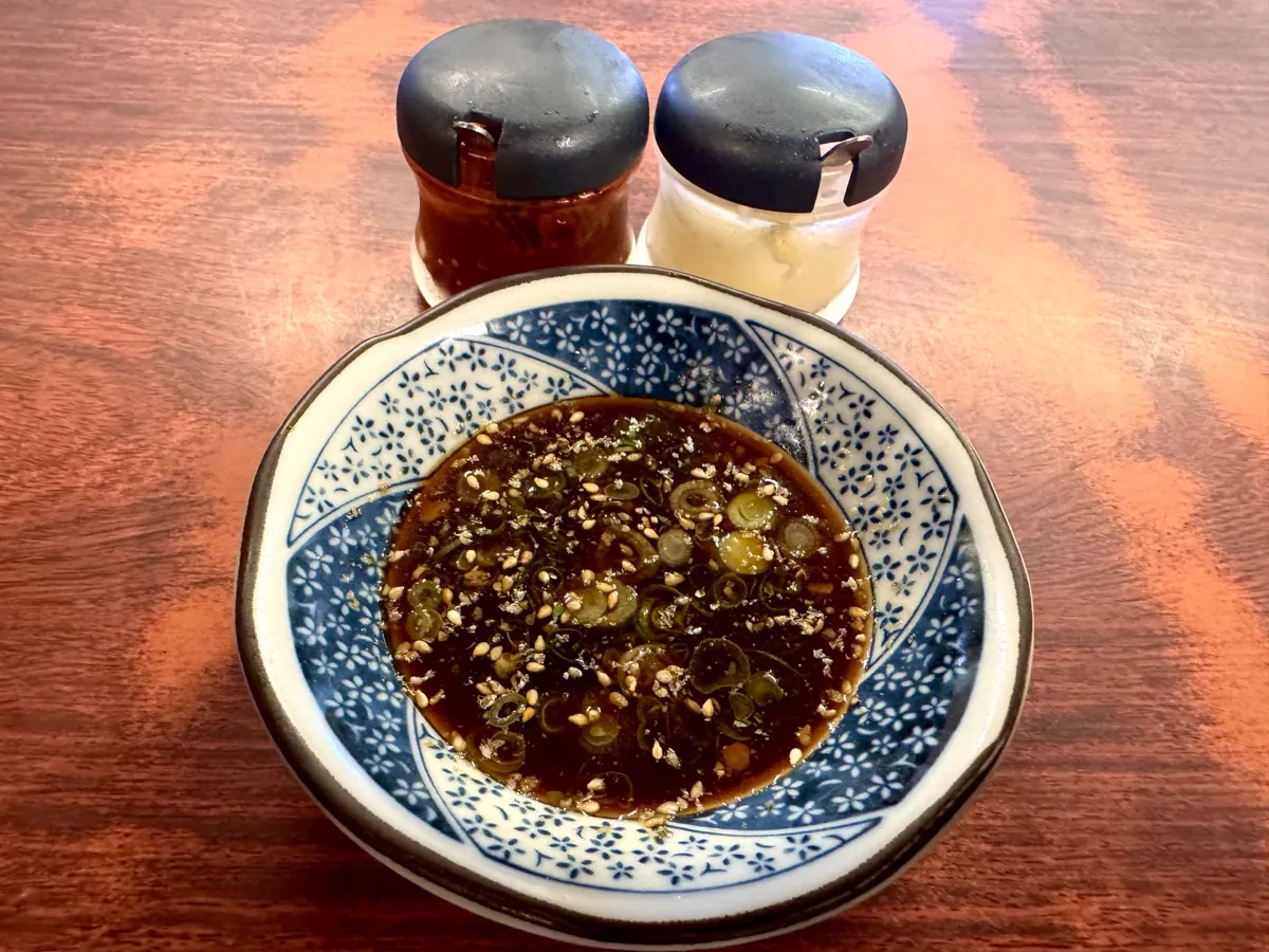 小皿に入れた2代目のタレ。薬味とごまが浮かぶ